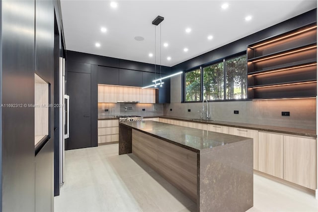 kitchen with a center island, sink, hanging light fixtures, tasteful backsplash, and dark stone countertops