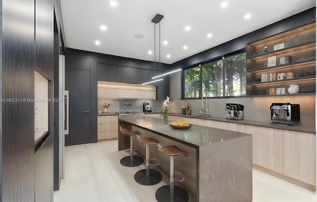 kitchen featuring a kitchen bar, backsplash, sink, a center island, and hanging light fixtures