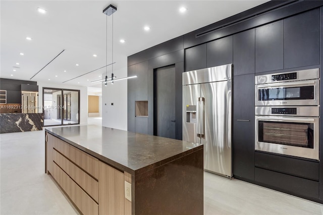 kitchen with hanging light fixtures, stainless steel appliances, a barn door, light brown cabinetry, and a kitchen island