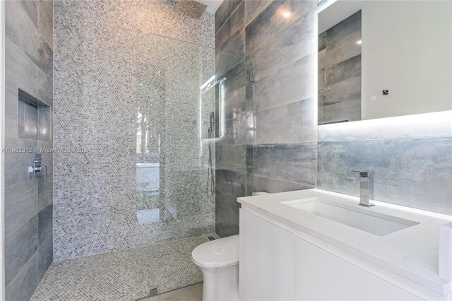 bathroom featuring tiled shower, vanity, tile walls, and toilet