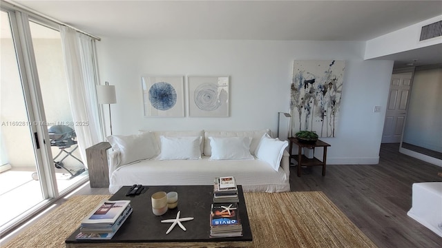 living area featuring wood finished floors, visible vents, and baseboards