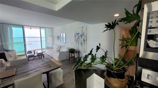 living room featuring expansive windows, wood-type flooring, and a water view