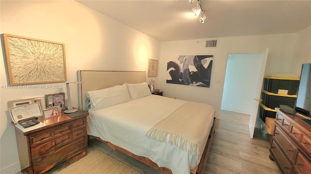 bedroom with visible vents, track lighting, and wood finished floors