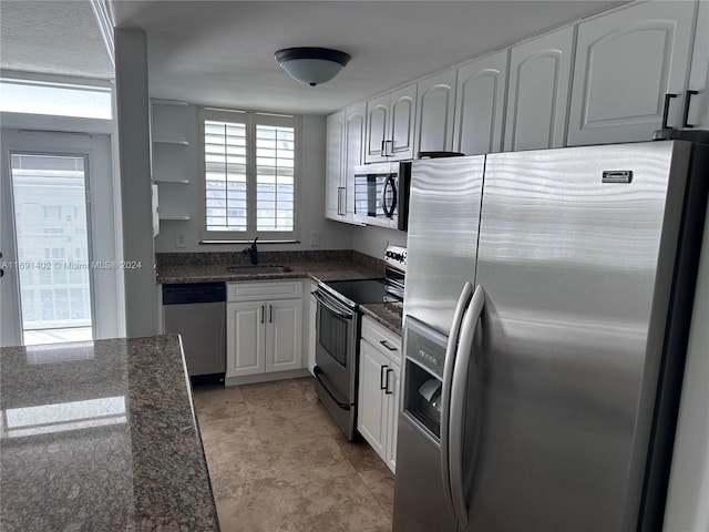 kitchen with dark stone countertops, white cabinetry, sink, and appliances with stainless steel finishes