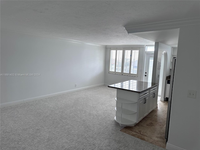 kitchen featuring white cabinets, a textured ceiling, light colored carpet, and a center island