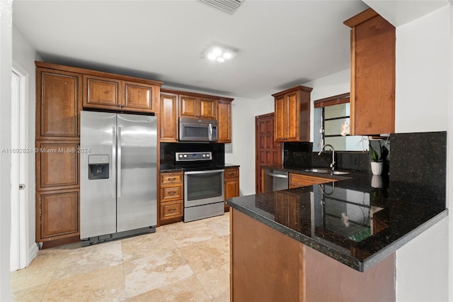 kitchen with kitchen peninsula, stainless steel appliances, tasteful backsplash, and dark stone countertops