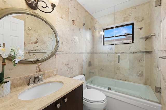 full bathroom with toilet, vanity, bath / shower combo with glass door, and tile walls