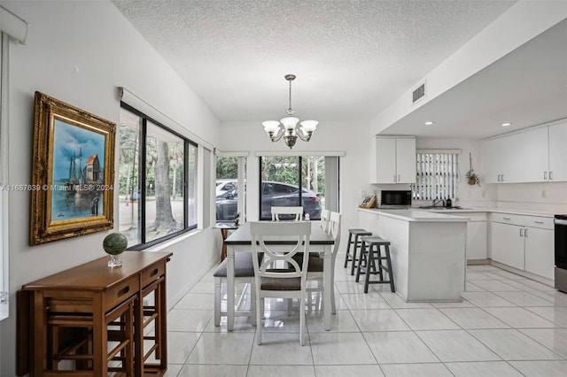 dining room featuring sink, a textured ceiling, a notable chandelier, and light tile patterned flooring