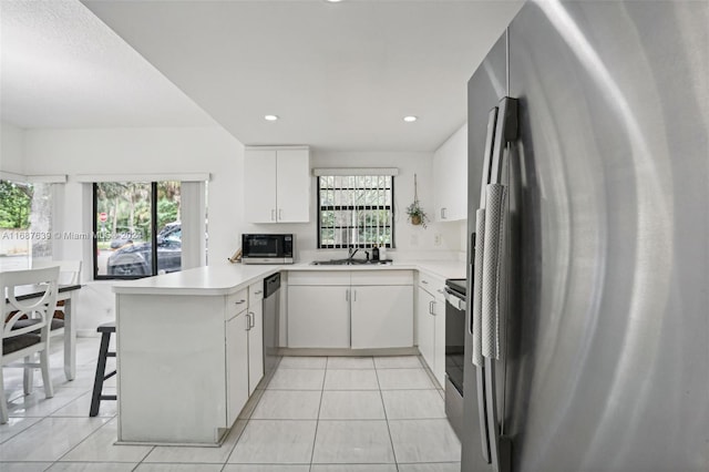 kitchen with appliances with stainless steel finishes, sink, a kitchen breakfast bar, white cabinets, and kitchen peninsula