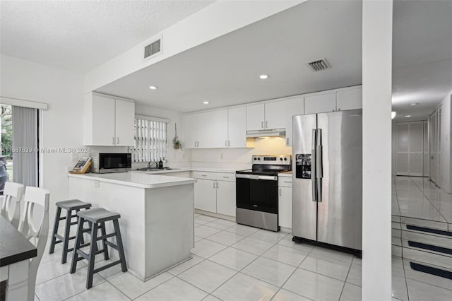 kitchen featuring white cabinetry, appliances with stainless steel finishes, a breakfast bar area, and kitchen peninsula