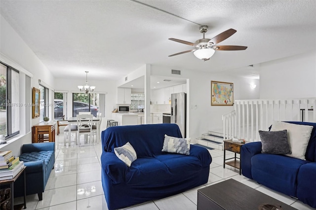 living room with a textured ceiling, ceiling fan with notable chandelier, and light tile patterned floors