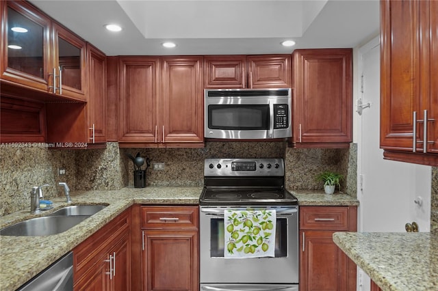 kitchen featuring decorative backsplash, stainless steel appliances, sink, and light stone counters