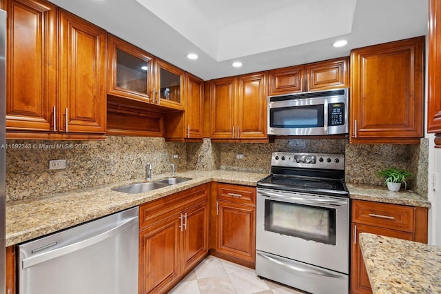 kitchen with appliances with stainless steel finishes, tasteful backsplash, light stone counters, and a tray ceiling