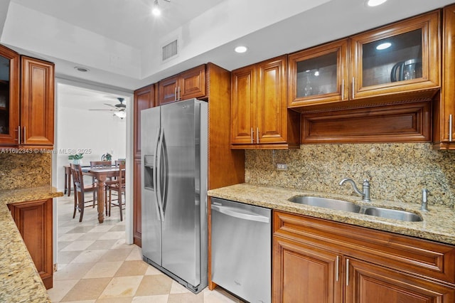 kitchen with appliances with stainless steel finishes, light stone countertops, sink, and decorative backsplash