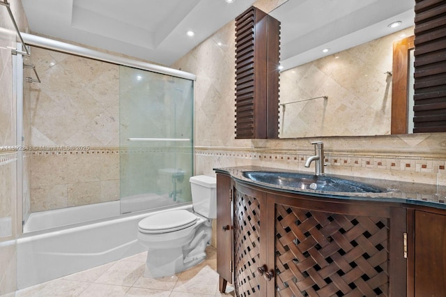 full bathroom with tile patterned floors, toilet, combined bath / shower with glass door, tile walls, and vanity