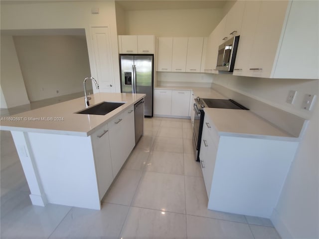 kitchen with stainless steel appliances, white cabinets, sink, and an island with sink