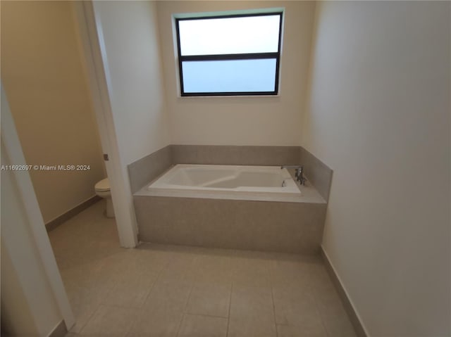 bathroom featuring tiled bath, tile patterned floors, and toilet