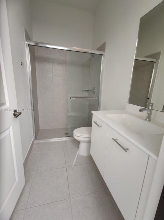 bathroom with toilet, vanity, tile patterned floors, and a shower with door