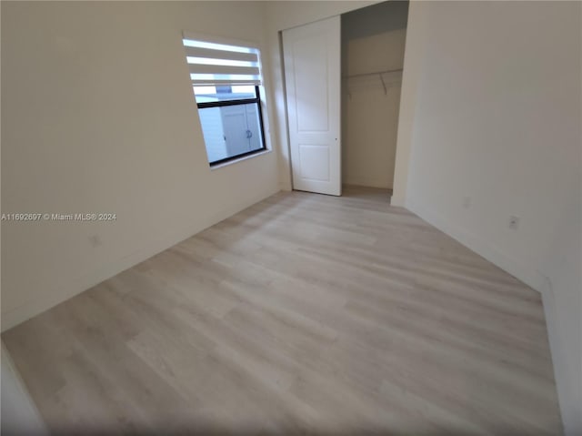 unfurnished bedroom featuring light hardwood / wood-style floors and a closet