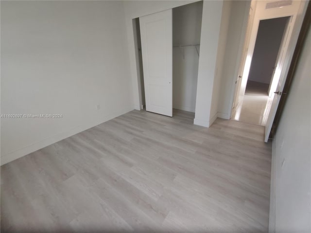 unfurnished bedroom featuring light hardwood / wood-style floors and a closet