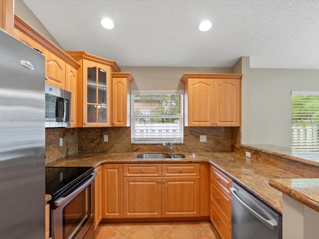 kitchen featuring decorative backsplash, stainless steel appliances, light stone counters, and sink