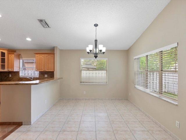 kitchen with light tile patterned flooring, backsplash, a wealth of natural light, and a chandelier