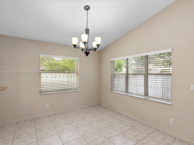 tiled spare room with a chandelier, a textured ceiling, vaulted ceiling, and plenty of natural light