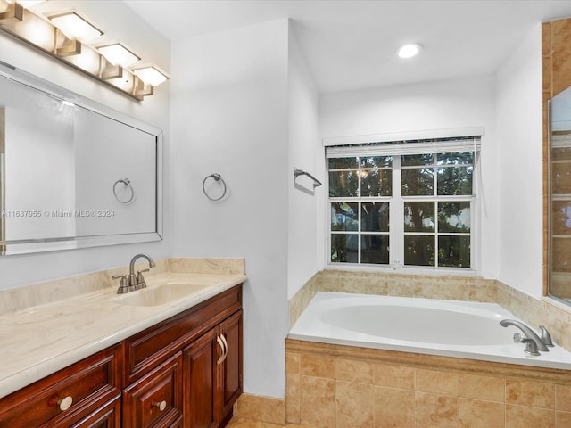 bathroom with tile patterned flooring, vanity, and tiled tub