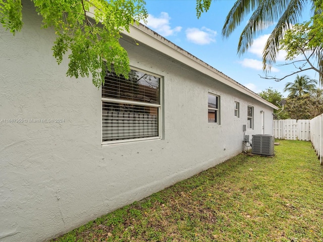 view of side of home with a lawn and central air condition unit