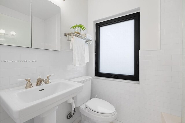 bathroom featuring sink, tile walls, and toilet