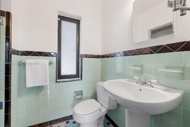 bathroom with tile walls, sink, and toilet