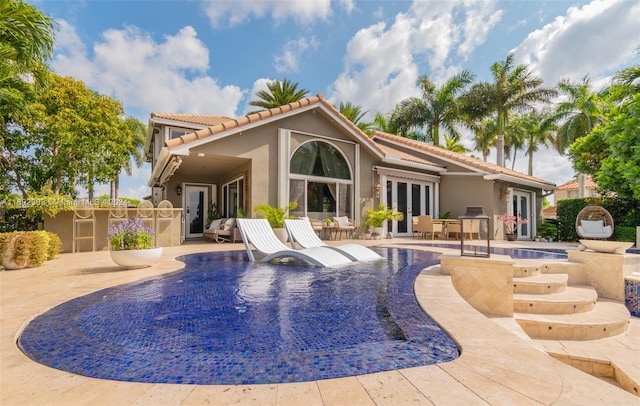 back of property featuring a patio and a pool with hot tub