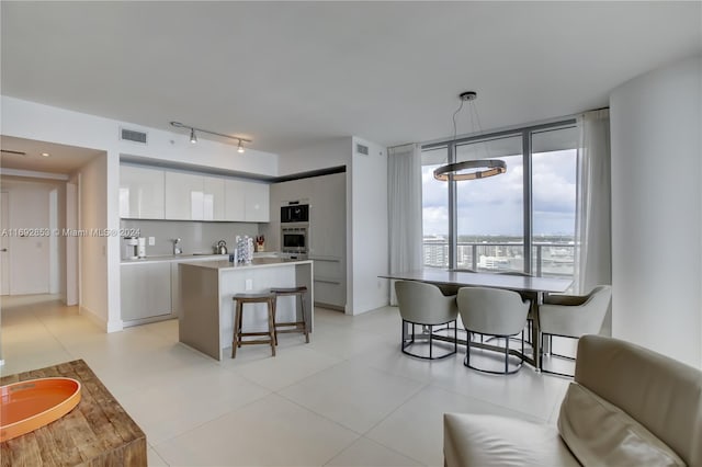 kitchen featuring white cabinetry, a kitchen bar, pendant lighting, oven, and a center island