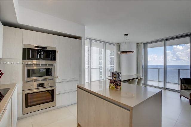 kitchen with hanging light fixtures, a water view, a center island, and floor to ceiling windows