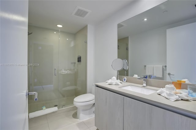 bathroom with vanity, a shower with door, tile patterned floors, and toilet