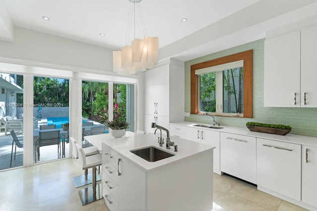 kitchen featuring white cabinetry, sink, and an island with sink