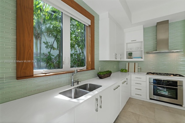 kitchen with wall chimney exhaust hood, sink, white cabinetry, and stainless steel appliances