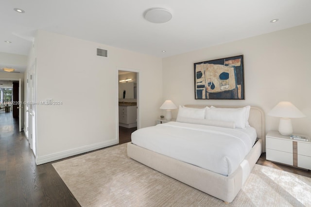 bedroom with hardwood / wood-style floors and ensuite bath