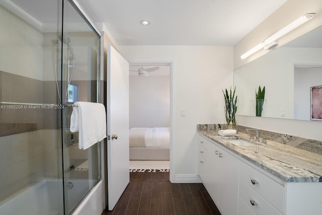 bathroom featuring hardwood / wood-style flooring, vanity, and bath / shower combo with glass door