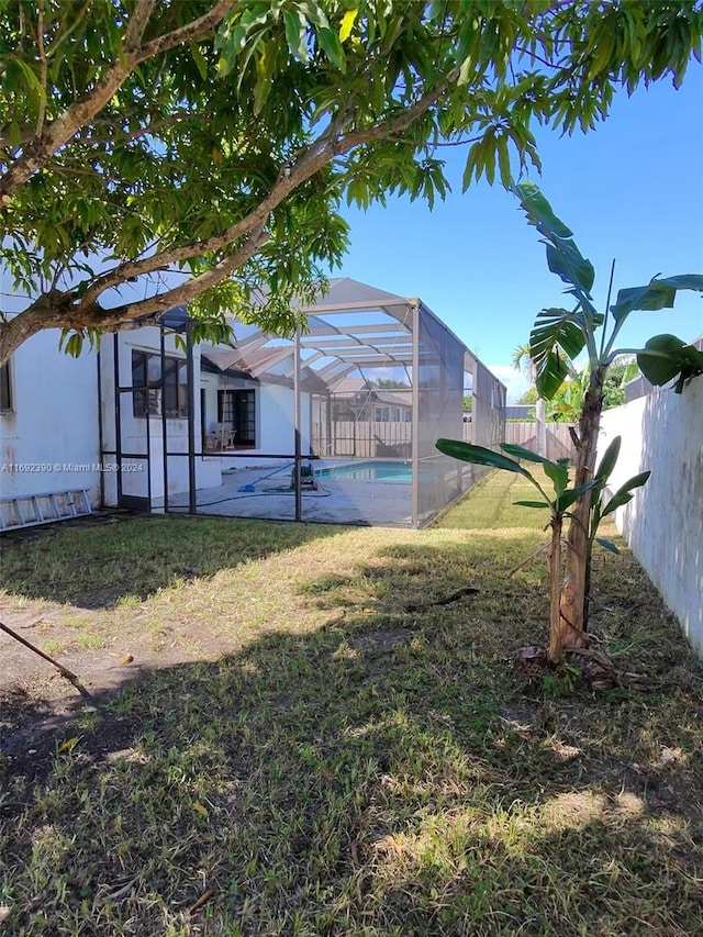 view of yard with glass enclosure, a patio, and a fenced in pool