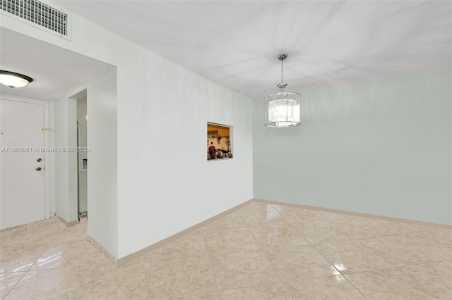 unfurnished dining area with a textured ceiling and a notable chandelier