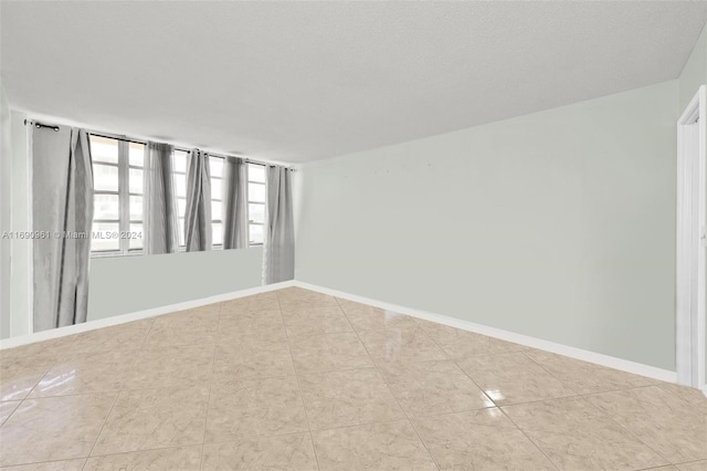 unfurnished room featuring light tile patterned flooring and a textured ceiling