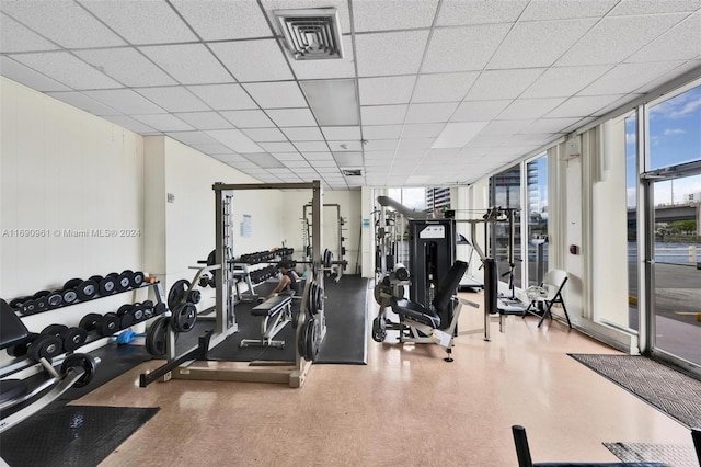 workout area with a drop ceiling and a wall of windows