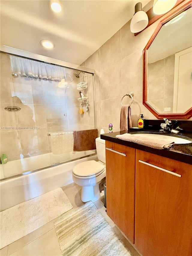 full bathroom with enclosed tub / shower combo, vanity, tile patterned floors, toilet, and tile walls