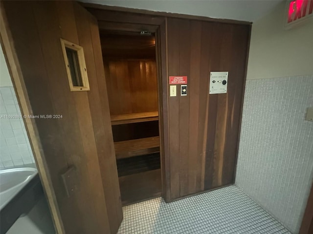 view of sauna featuring wood walls and tile patterned flooring