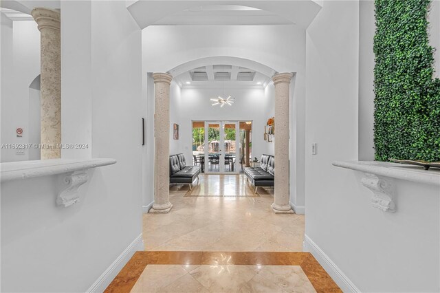 hall with ornate columns, french doors, beamed ceiling, and an inviting chandelier