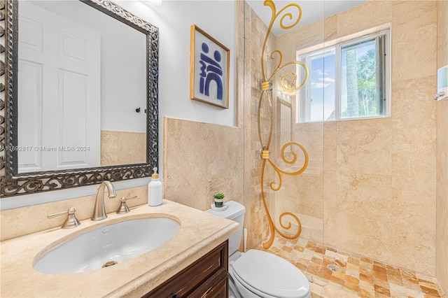 bathroom with toilet, vanity, and a tile shower