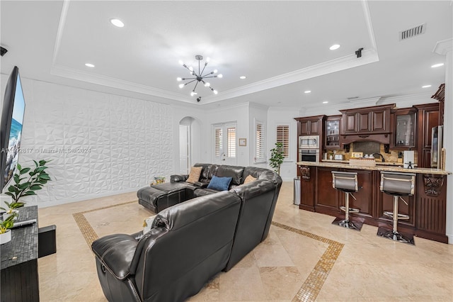 living room featuring a chandelier, a raised ceiling, and crown molding