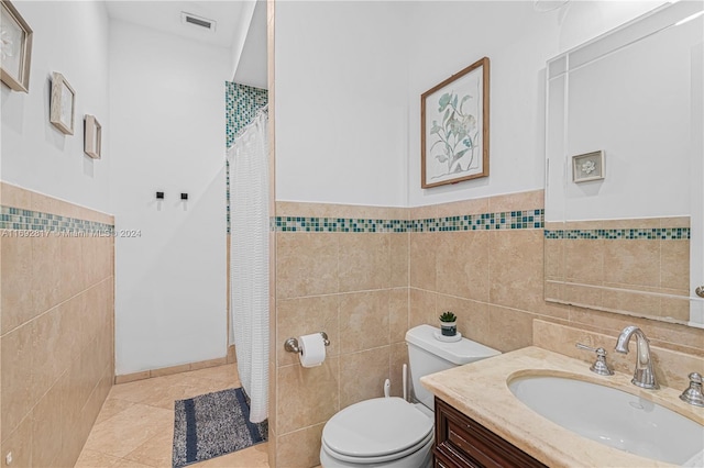 bathroom with tile patterned floors, toilet, tile walls, curtained shower, and vanity