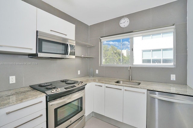 kitchen featuring white cabinets, stainless steel appliances, sink, and light stone counters